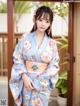 A woman in a blue kimono standing in front of a door.