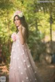 A woman in a pink dress standing on a swing.