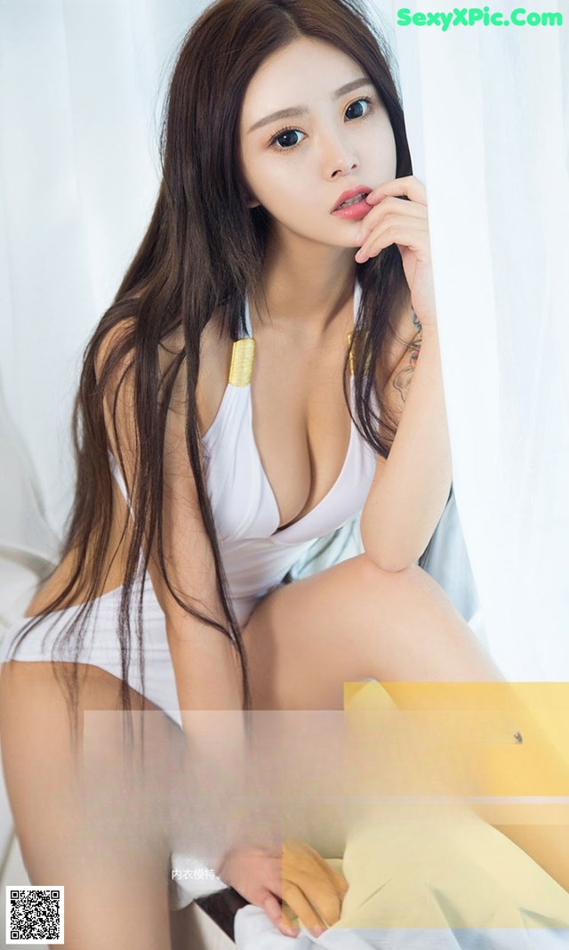 A woman in a white dress sitting on a bed.