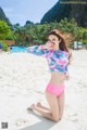 A woman in a pink bikini sitting on a beach.