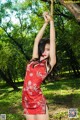 A woman in a red dress is tied up to a tree.