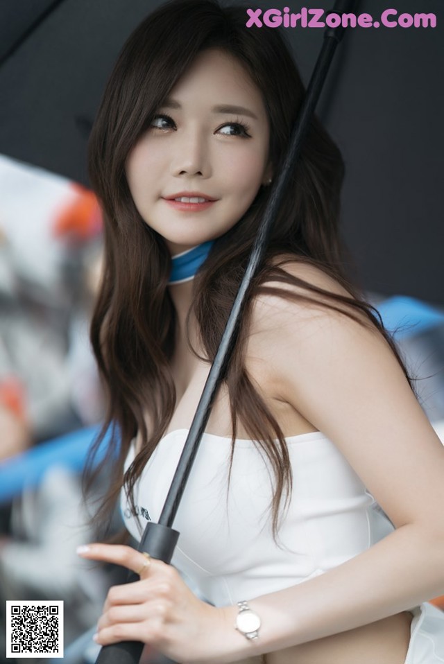 A woman in a white dress holding an umbrella.