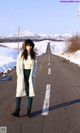 A woman standing on the side of a road in the snow.