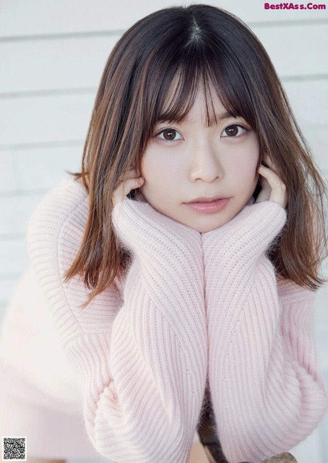 A woman in a pink sweater sitting on a chair.