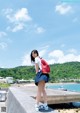 A young woman with a red backpack standing on a concrete wall.