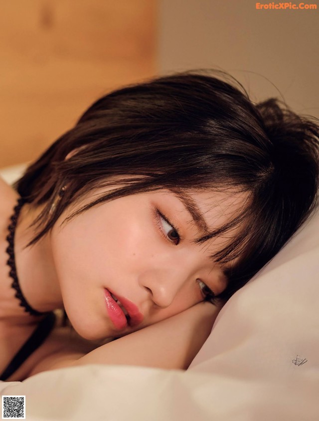 A woman laying on top of a bed next to a pillow.
