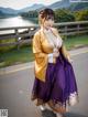 A woman in a purple and gold kimono is posing for a picture.