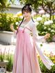 A woman in a pink and white hanbok is posing for a picture.