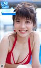 A woman in a red bikini sitting in a pool.